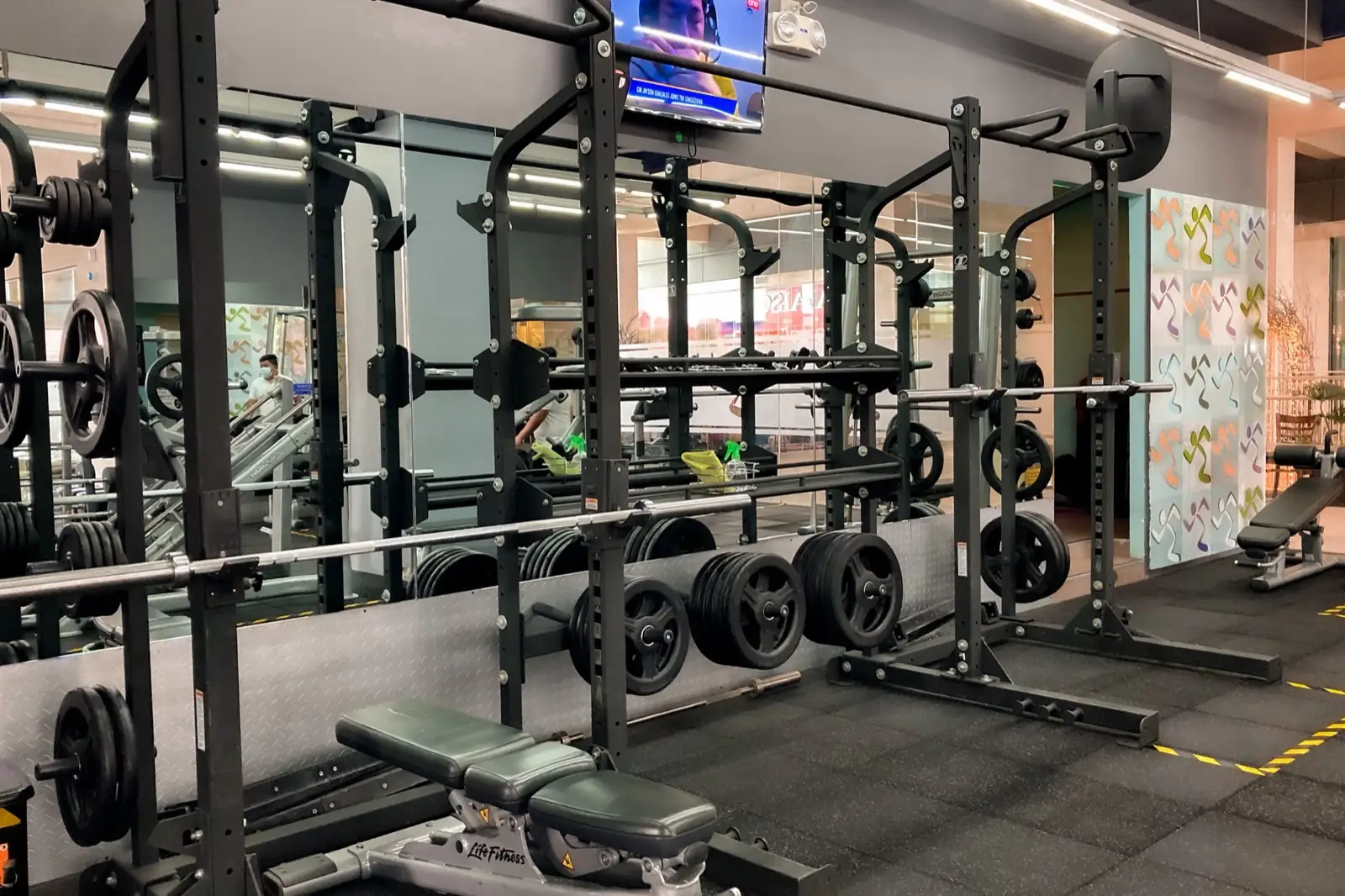 Una sala de musculación con racks de sentadilla, barras cargadas y bancos
